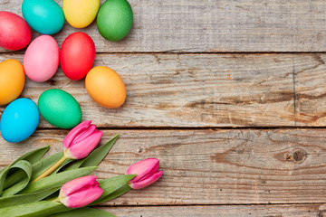 Colorful easter eggs and tulips on wooden table