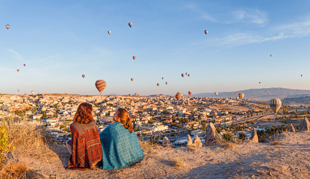 Couple of friends travelers enjoying valley view with wonderful balloons flight over Cappadocia valley in Turkey