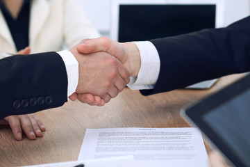 Close up of business people shaking hands at meeting or negotiation in the office. Partners are satisfied because signing contract