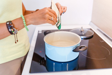 Hand pour the spices into the pan in modern kitchen with induction stove