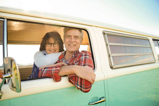 Portrait of cheerful senior couple sitting in vintage camper van