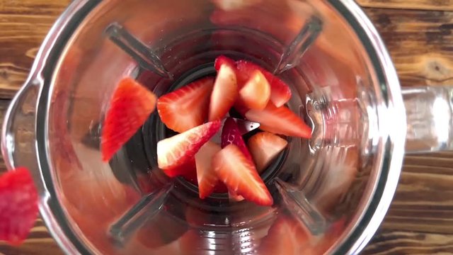 Fresh ripe strawberries pouring in a blender, super slow motion video
