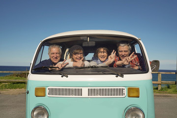 Portrait of senior people through vintage camper van windshield