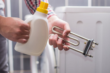 
a man holds in his hand the heating elements of the washing machine and the descaling agent or...