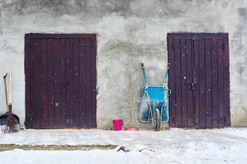 Old countryside wall with two wooden doors and wheelbarrow