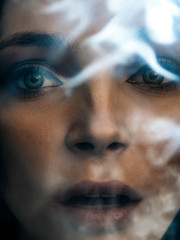 fashion portrait of a beautiful young woman who exhales smoke