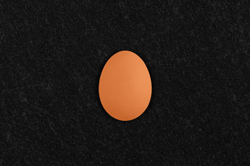raw hen egg on black slate background