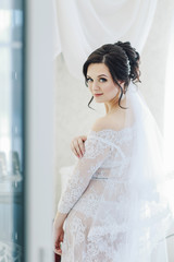 portrait of a beautiful cute bride in a boudoir in a bright morning room