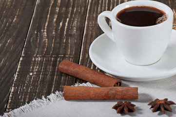 Food - a cup of hot aromatic coffee and spices on an old wooden background.