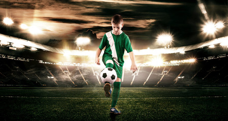 Kid - soccer player. Boy forward in football sportswear on stadium with ball. Sport concept.