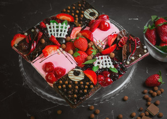 Fresh berry strawberry chocolate cakes in assortment. Ingredients for berry cakes are fresh strawberries, pieces of chocolate. Dark background.
