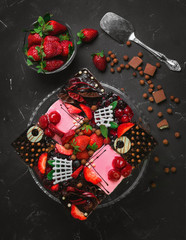 Obraz na płótnie Canvas Fresh berry strawberry chocolate cakes in assortment. Ingredients for berry cakes are fresh strawberries, pieces of chocolate. Dark background. Top view.