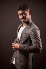 side view photography of smiling African man trying on coat isolated on the black background