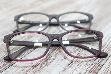 Two pairs of stylish women's eyeglass frames on white wooden background