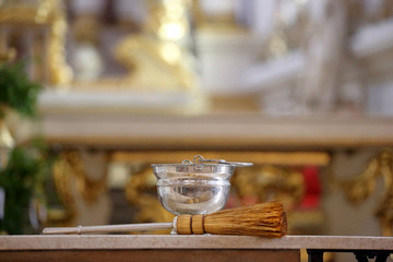 Church interior with  sprinkler and holy water during Easter with empty space for text