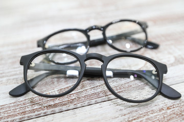 Two pairs of fashionable men's eyeglass frames on white wooden background