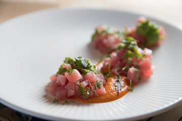 Tuna tartare with green sauce on a white plate