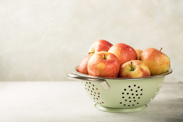 Fresh red apples in green metal strainer on light background. Healthy food concept with copy space.