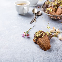 Homemade chocolate cookies Madeleine with chopped pistachio nuts in metal basket. Holidays and party food concept with copy space.