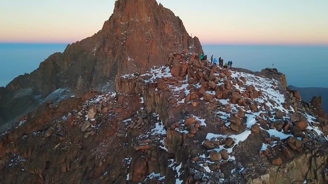 aerial view of unrecognizible climbers on summit of the Lenana peak of Mount Kenya during sunrise