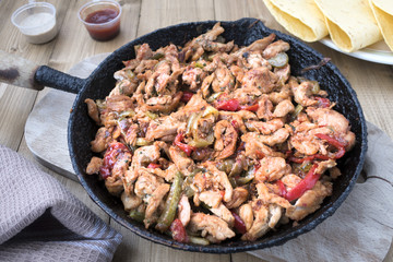 Chicken stew with red and green pepper, with red onion, pickled cucumber and spices in a frying pan.