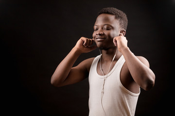 close up side view photo of African man with headphones on his ears enjoy music with closed eyes on the black background.melomaniac