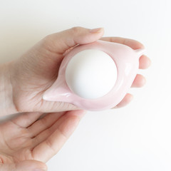 Woman's hands holding egg stand with white egg. Top view. Easter Composition
