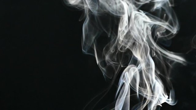 A beautiful gray smoke slowly flies in the room. Cigarette smoke on a black background. Steam rises up. Textured fog.