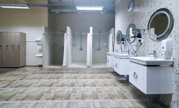 Public shower interior with everal showers, toilet sink and lockers in locker room in luxury fitness spa centre