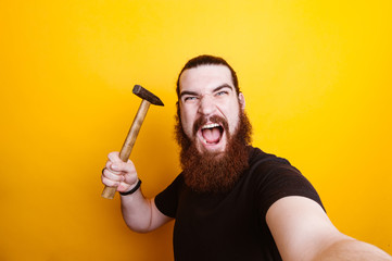 Angry bearded man with hammer making selfie