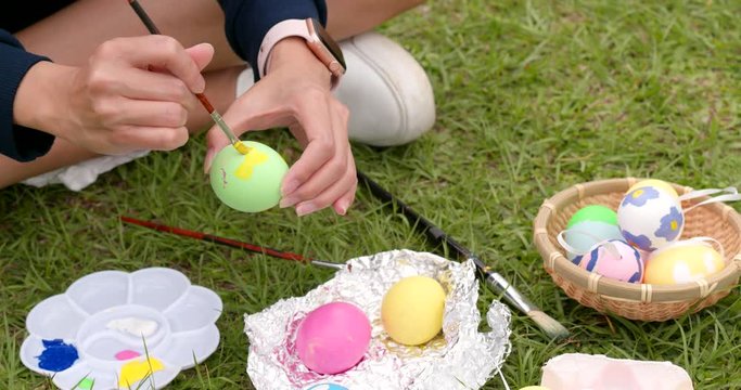 Painting Easter egg on green grass