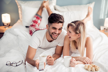 Happy man and woman having breakfast in bed