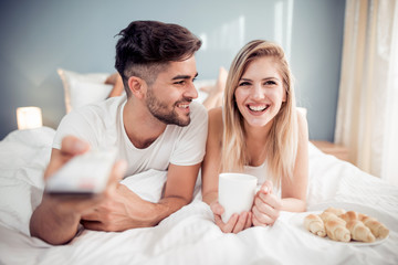 Happy man and woman having breakfast in bed