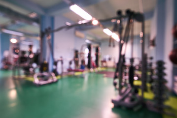Blurred interior of fitness center. Sport exercise equipment for bodybuilding weight and dumbbells in gym room