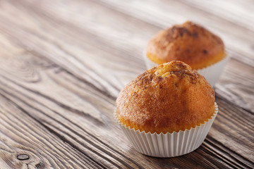 Classic muffins on a wooden old background in a white wrapper.