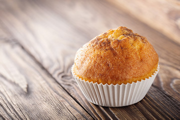 Classic muffins on a wooden old background in a white wrapper.