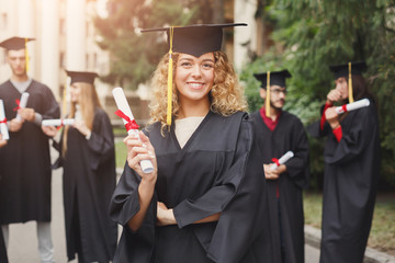 Happy young woman on her graduation day. - obrazy, fototapety, plakaty