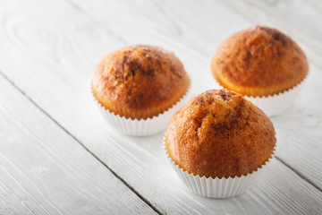 Classic muffins on a wooden old white background in a white wrapper.