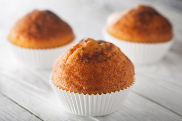 Classic muffins on a wooden old white background in a white wrapper.