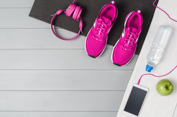 Fototapeta na wymiar Sport and fitness accessories, healthy and active lifestyle concept on grey wooden floor background with copy space. Products with vibrant, punchy pastel colours. Image taken from above, top view.