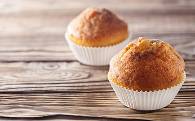 Classic muffins on a wooden old background in a white wrapper.