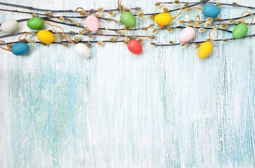 Easter background. Willow branch and decorative Easter eggs on blue background. Top view, copy space