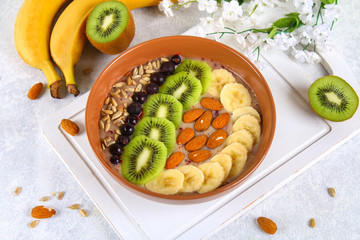 Breakfast berry smoothie bowl topped with bananas, berries, kiwi, almonds and sunflower seeds.