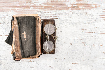 Ancient prayer book with round spectacles 1920s and case on the wooden table, top view, space for...