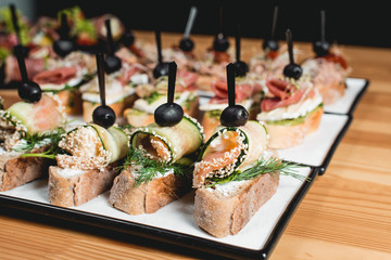 tasty pinchos with tuna, chorizos, salmon, egg, dried tomatoes, avocado, salmon, bacon, Hamon, Brie Cheese, Olives and Pesto Sauce, traditional spanish snack