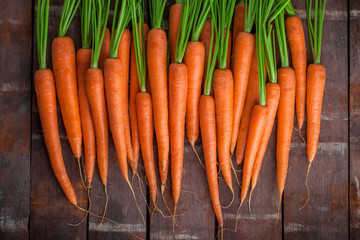 Carrot fresh  vibrant color arrangement overhead lined up on brown rustic wooden table in studio
