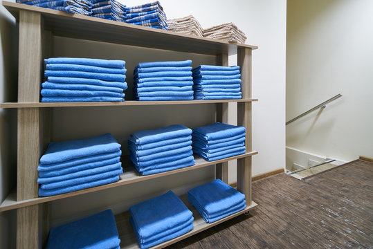 Shelf with a stacked blue clean bath towels in laundry 