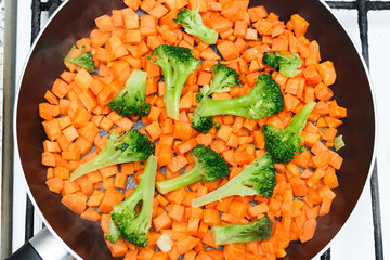 Fresh vegetables in a frying pan. Fresh vegetable products, freshly frozen odietic vegetables, broccoli, carrots are cooked in a frying pan on a gas stove.