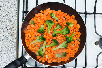 Fresh vegetables in a frying pan. Fresh vegetable products, freshly frozen odietic vegetables, broccoli, carrots are cooked in a frying pan on a gas stove.