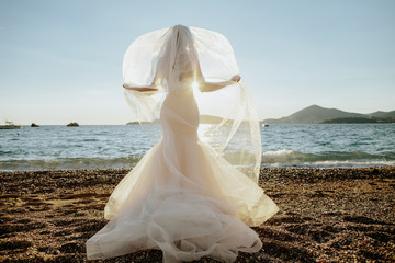 Fototapeta na wymiar Bride in beautiful dress on beach with sea view
